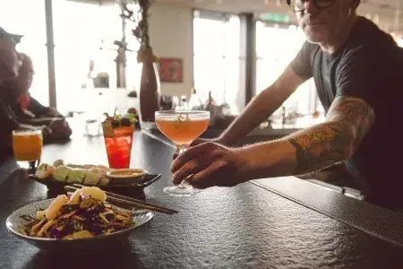 A bartender serves a patron a cocktail at a bar in San Francisco.